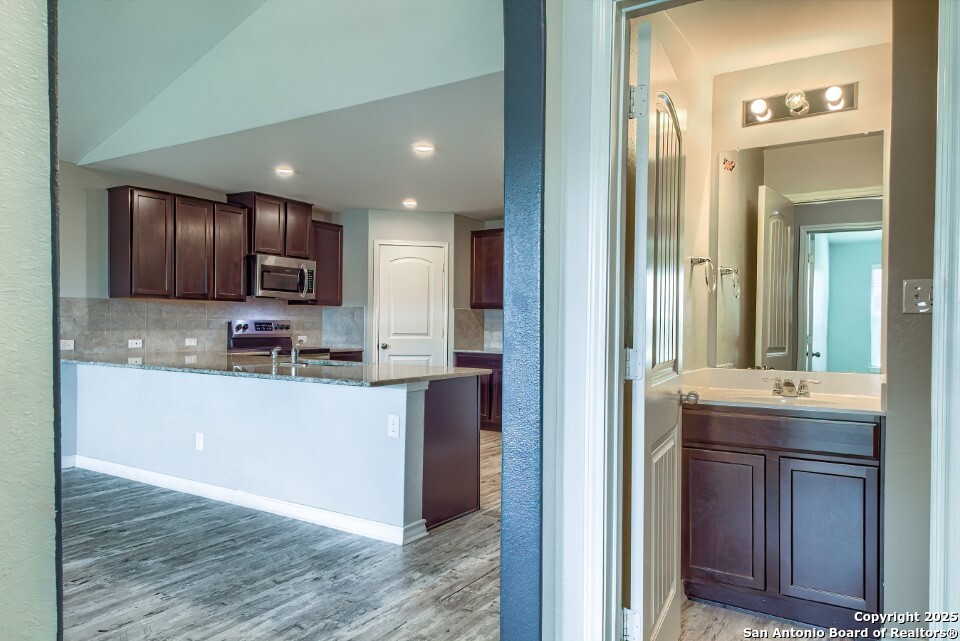 7006 Quantum Loop San Antonio, TX 78252 - Photo 12 of 37 a kitchen with kitchen island granite countertop wooden cabinets a sink and stainless steel appliances