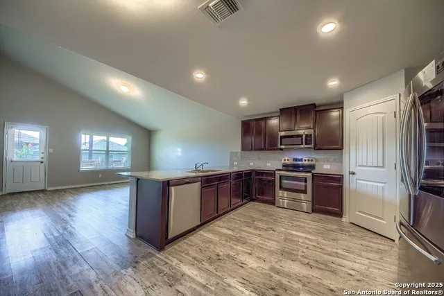 a kitchen with stainless steel appliances granite countertop a refrigerator stove top oven and sink