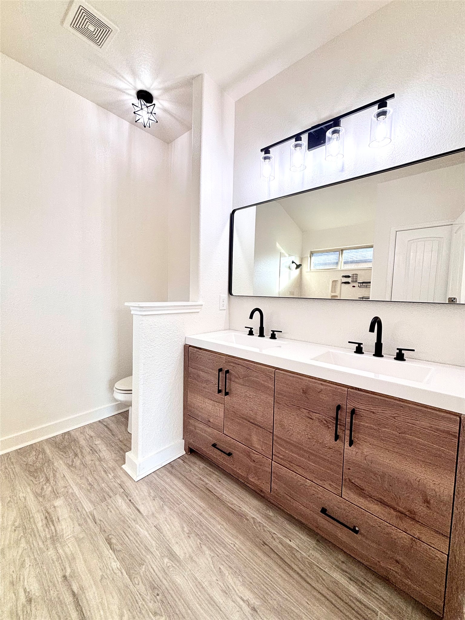 606 Old Peak Road Georgetown, TX 78626 - Photo 18 of 23 Modern double vanity with dark hardware and light wood-look flooring defines this fresh bathroom space.