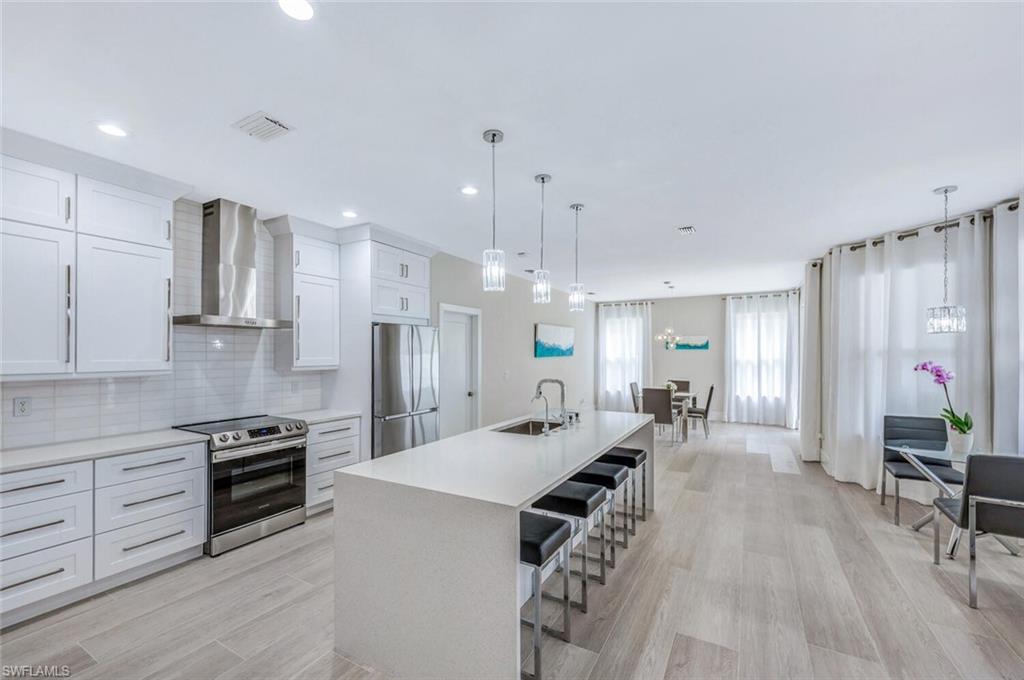 8260 Laurel Lakes Boulevard Naples, FL 34119 - Photo 11 of 41 a large kitchen with cabinets chairs and wooden floor