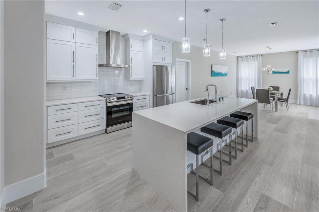 8260 Laurel Lakes Boulevard Naples, FL 34119 - Photo 13 of 41 a kitchen with kitchen island a stove a table and chairs in it
