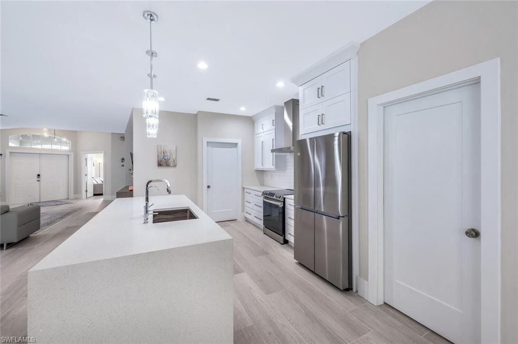 8260 Laurel Lakes Boulevard Naples, FL 34119 - Photo 39 of 41 a kitchen with stainless steel appliances a refrigerator sink and wooden floor