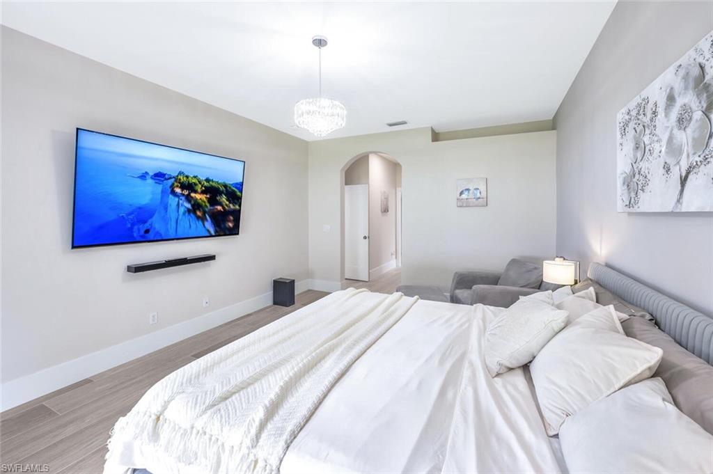 8260 Laurel Lakes Boulevard Naples, FL 34119 - Photo 20 of 41 a bedroom with a large bed and a chandelier
