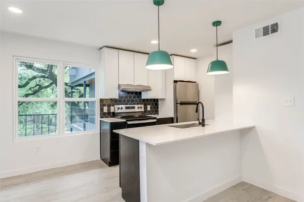 a kitchen with kitchen island a counter space a sink appliances and a window
