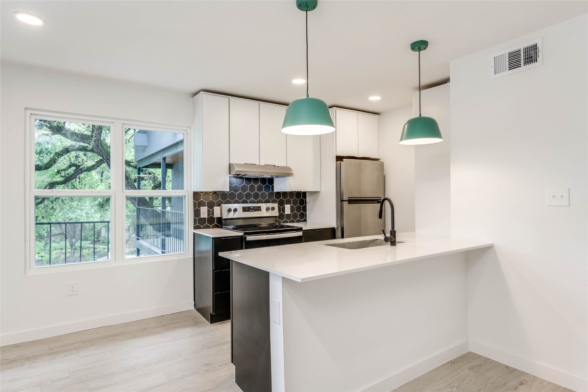 a kitchen with kitchen island a counter space a sink appliances and a window