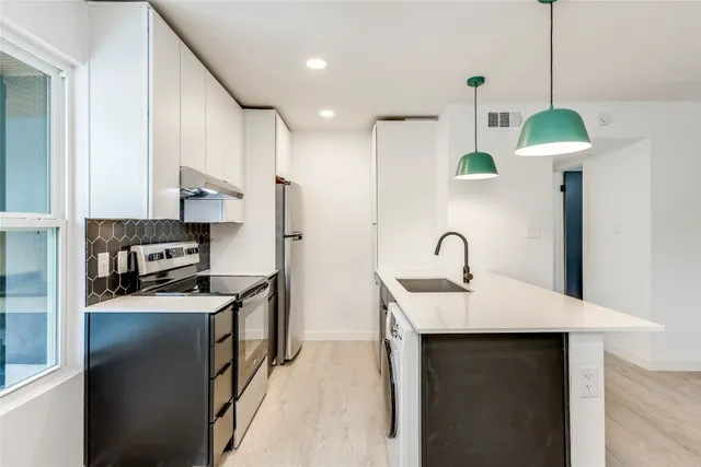a kitchen with stainless steel appliances a table chairs in it and wooden floors