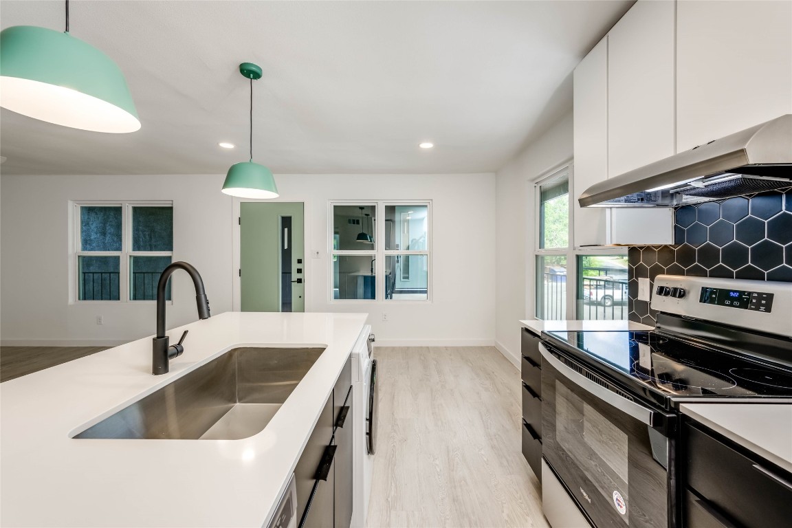 513 Pecan Grove Road, Unit 102 Austin, TX 78704 - Photo 3 of 15 a kitchen with kitchen island granite countertop a sink stainless steel appliances and cabinets