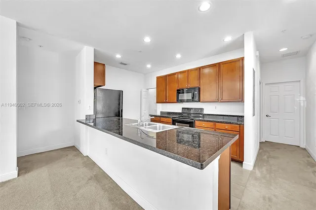 a kitchen with stainless steel appliances granite countertop a sink a stove and a microwave
