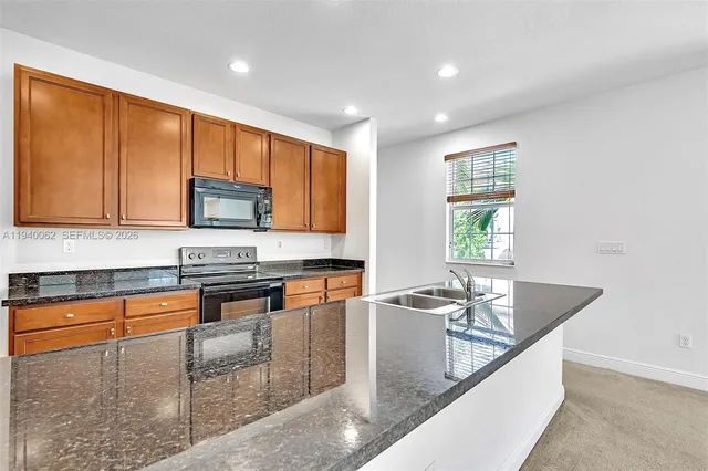 a kitchen with stainless steel appliances granite countertop a sink a microwave a refrigerator and a stove