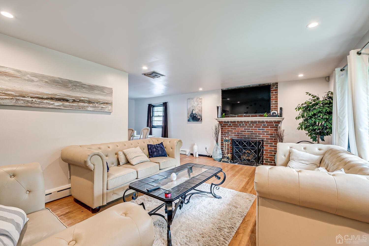319 Chain O' Hills Road Colonia, NJ 07067 - Photo 8 of 37 a living room with furniture a fireplace and a flat screen tv