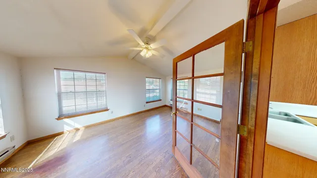 a view of an empty room with wooden floor and a window