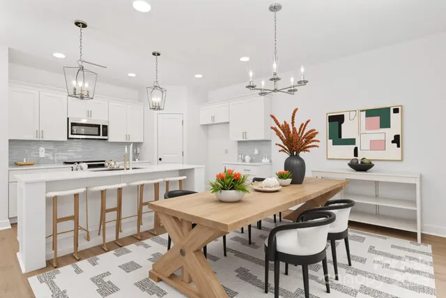 a kitchen with kitchen island a dining table chairs sink and stove