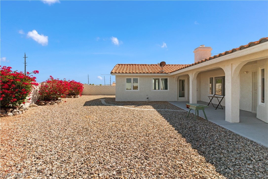 2055 Cholla Way Laughlin, NV 89029 - Photo 55 of 87 A spacious gravel yard, accented by vibrant red bougainvillea and a classic Spanish-style tiled roof.