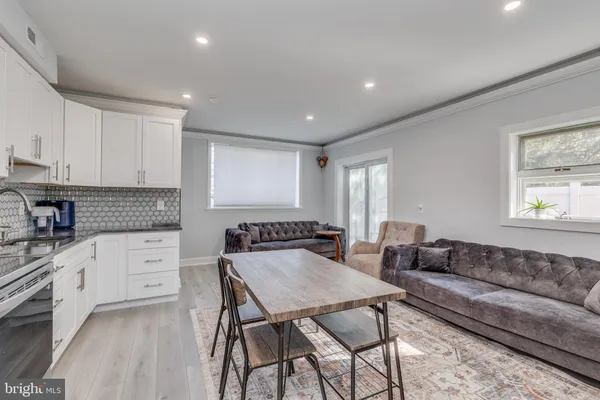 a living room with kitchen island furniture a stove a sink and white cabinets