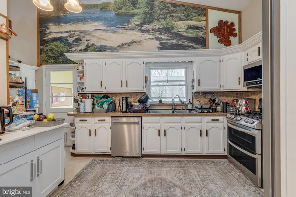 a kitchen with stainless steel appliances granite countertop a stove a sink and white cabinets