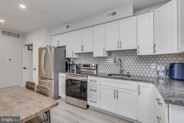 a kitchen with white cabinets and stainless steel appliances