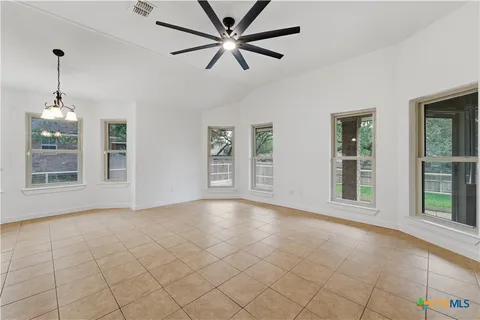 a view of an empty room with window and chandelier fan