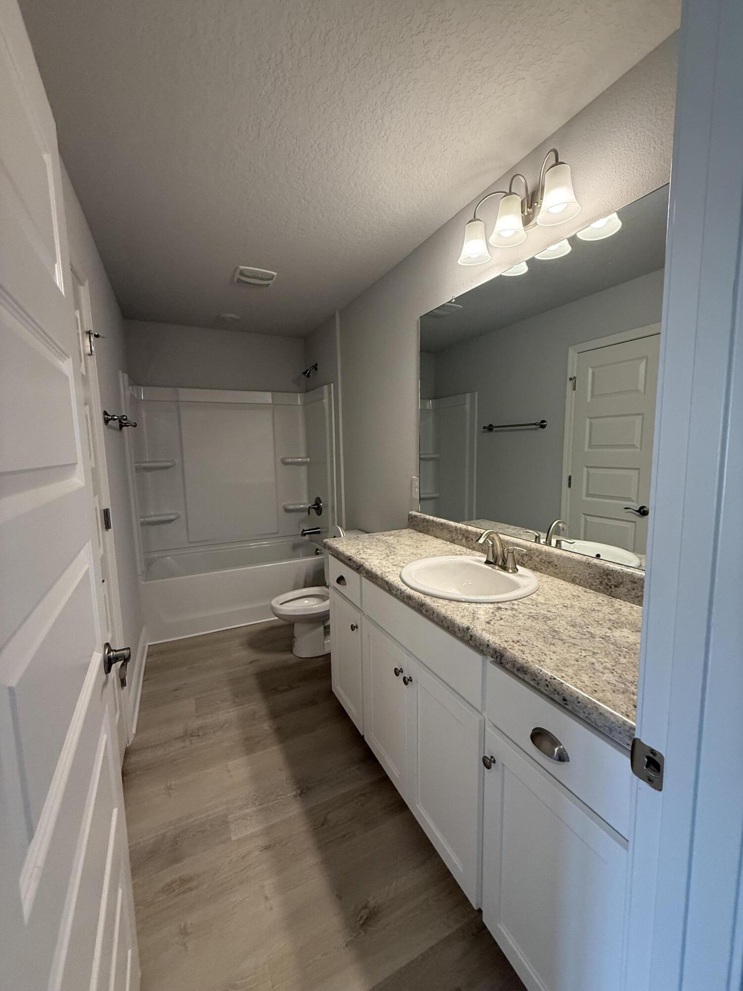 6002 Crocket Cove Crestview, FL 32539 - Photo 10 of 29 a bathroom with a granite countertop double vanity sink a mirror and a shower