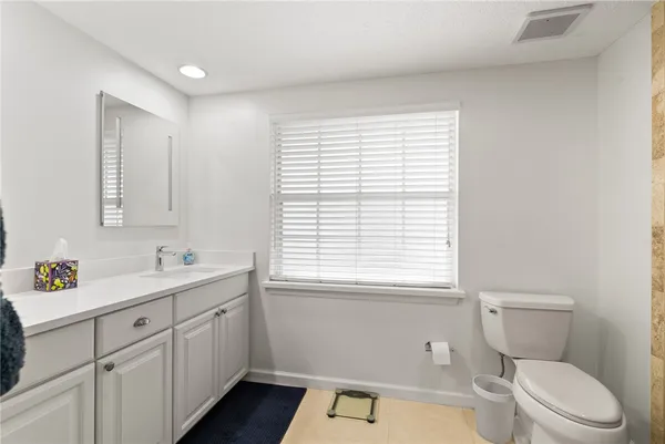 a bathroom with a toilet a sink a vanity a window and mirror