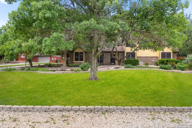 a front view of a house with a garden and trees