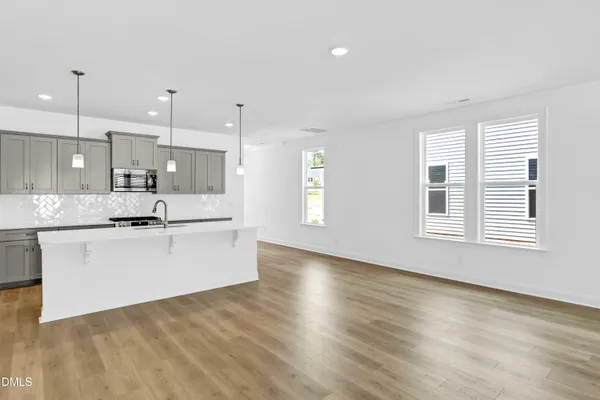 a large white kitchen with kitchen island a sink wooden floor and a window