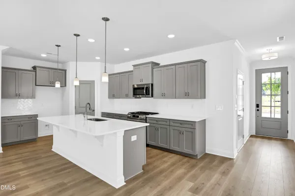 a large kitchen with stainless steel appliances granite countertop a sink a stove and a wooden floors