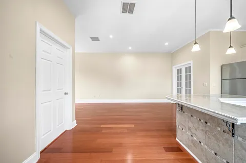 a view of an empty room with wooden floor and a window
