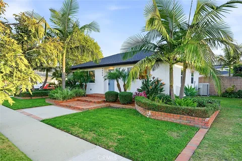 a view of a house with a yard and palm trees