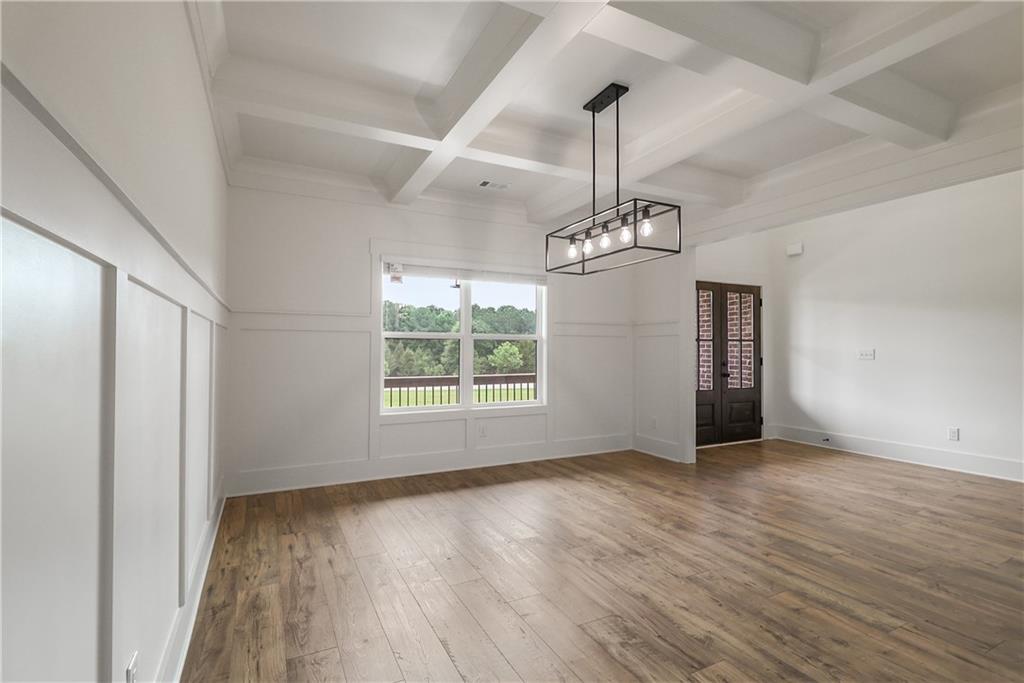 2113 Stonegate Way Monroe, GA 30656 - Photo 12 of 43 an empty room with wooden floor chandelier and windows
