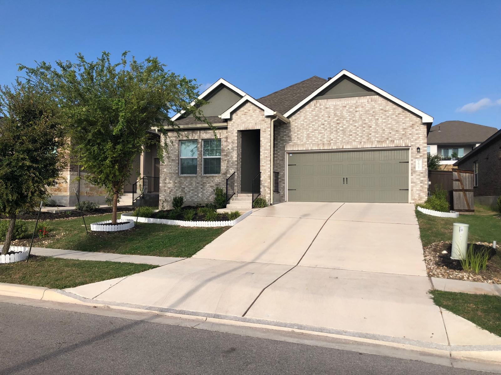 1621 Brueggerhoff Road Leander, TX 78641 - Photo 2 of 28 Brick facade with a contrasting gable accent, featuring a two-car garage with a paneled door