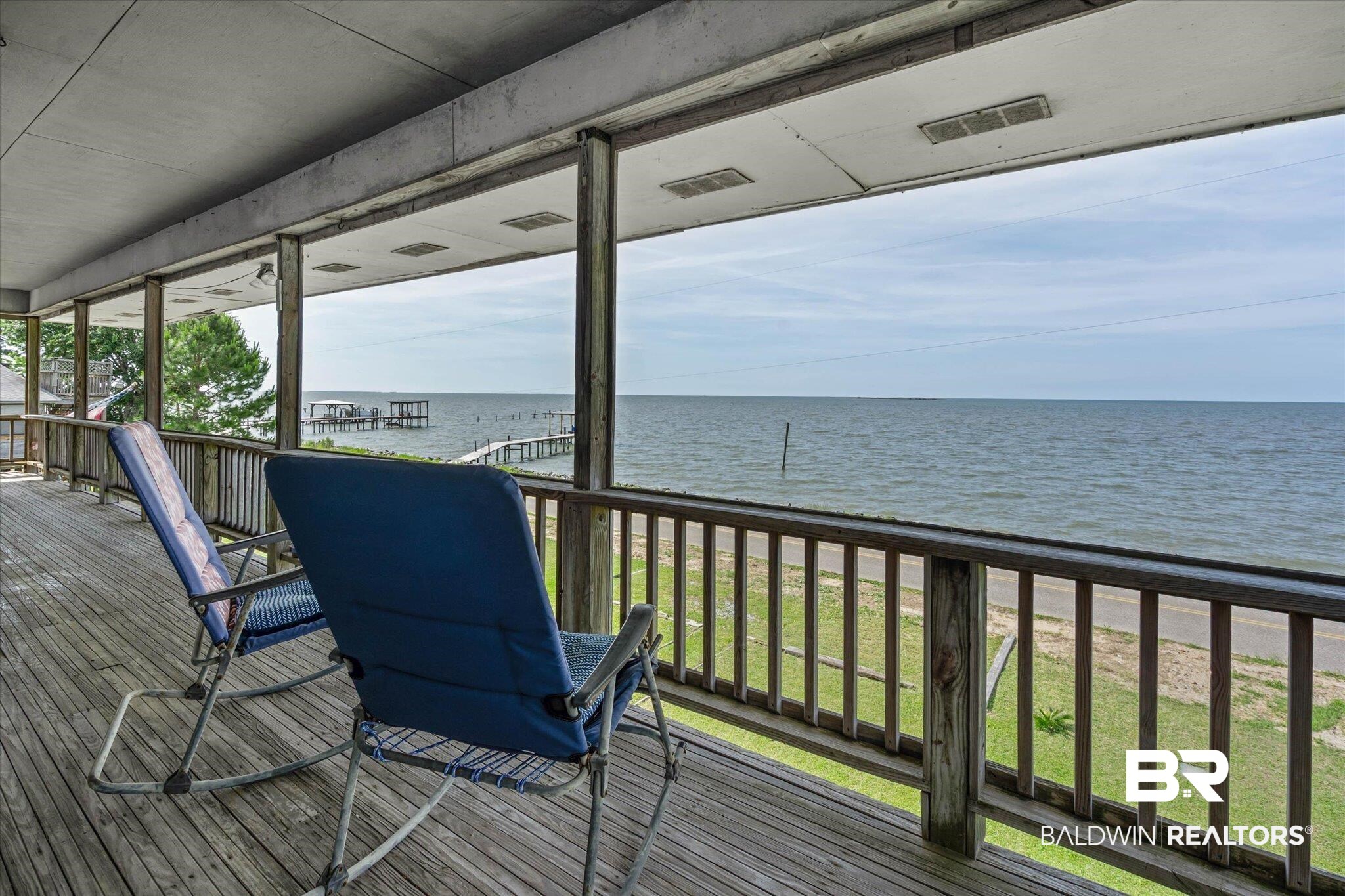 9100 Shell Belt Road Coden, AL 36523 - Photo 6 of 38 Expansive covered wood deck with water frontage, wood railing, and a visible pier structure