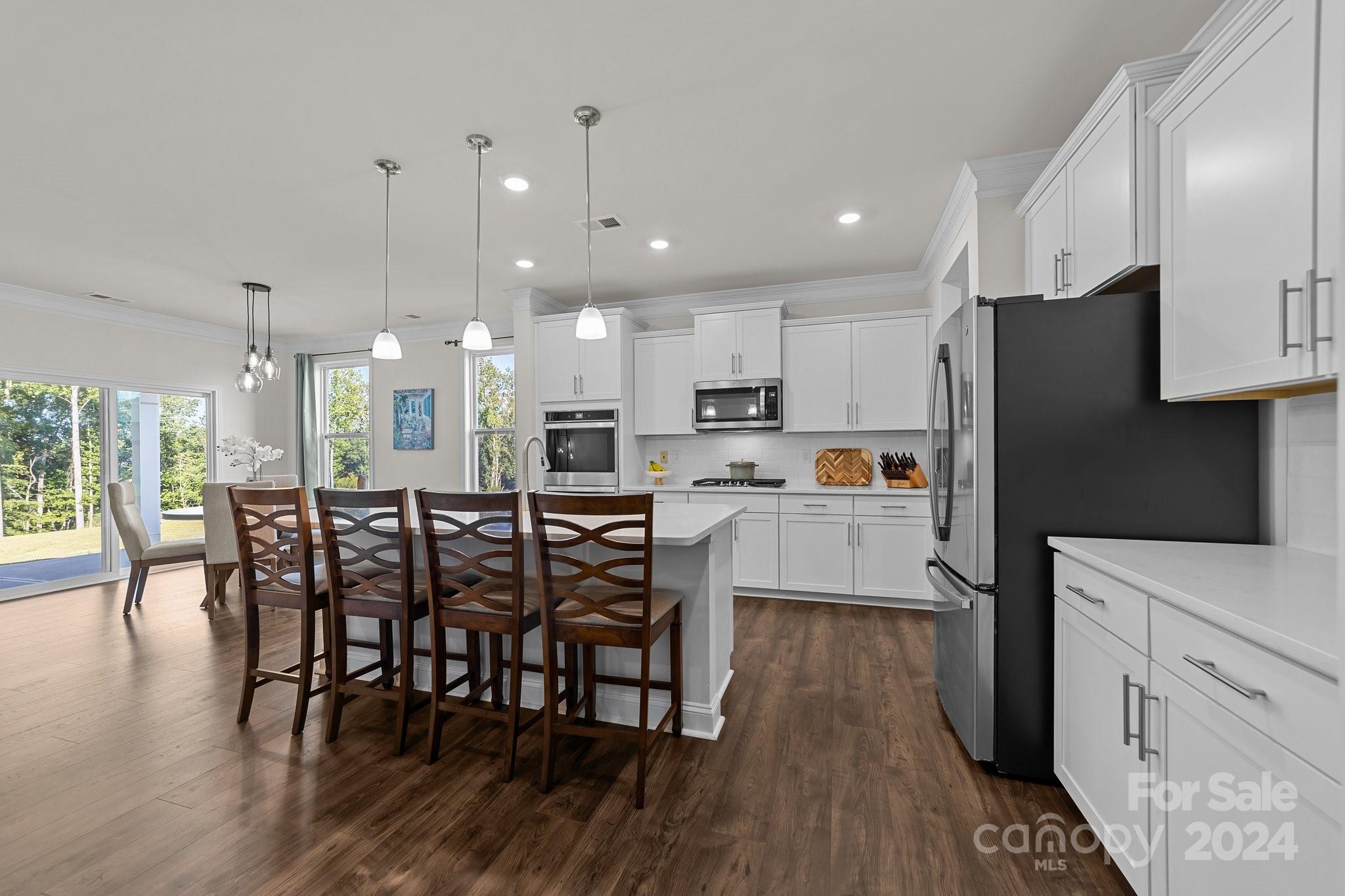 6037 Treehouse Drive Charlotte, NC 28214 - Photo 13 of 48 a kitchen with stainless steel appliances kitchen island granite countertop a wooden floor and white cabinets
