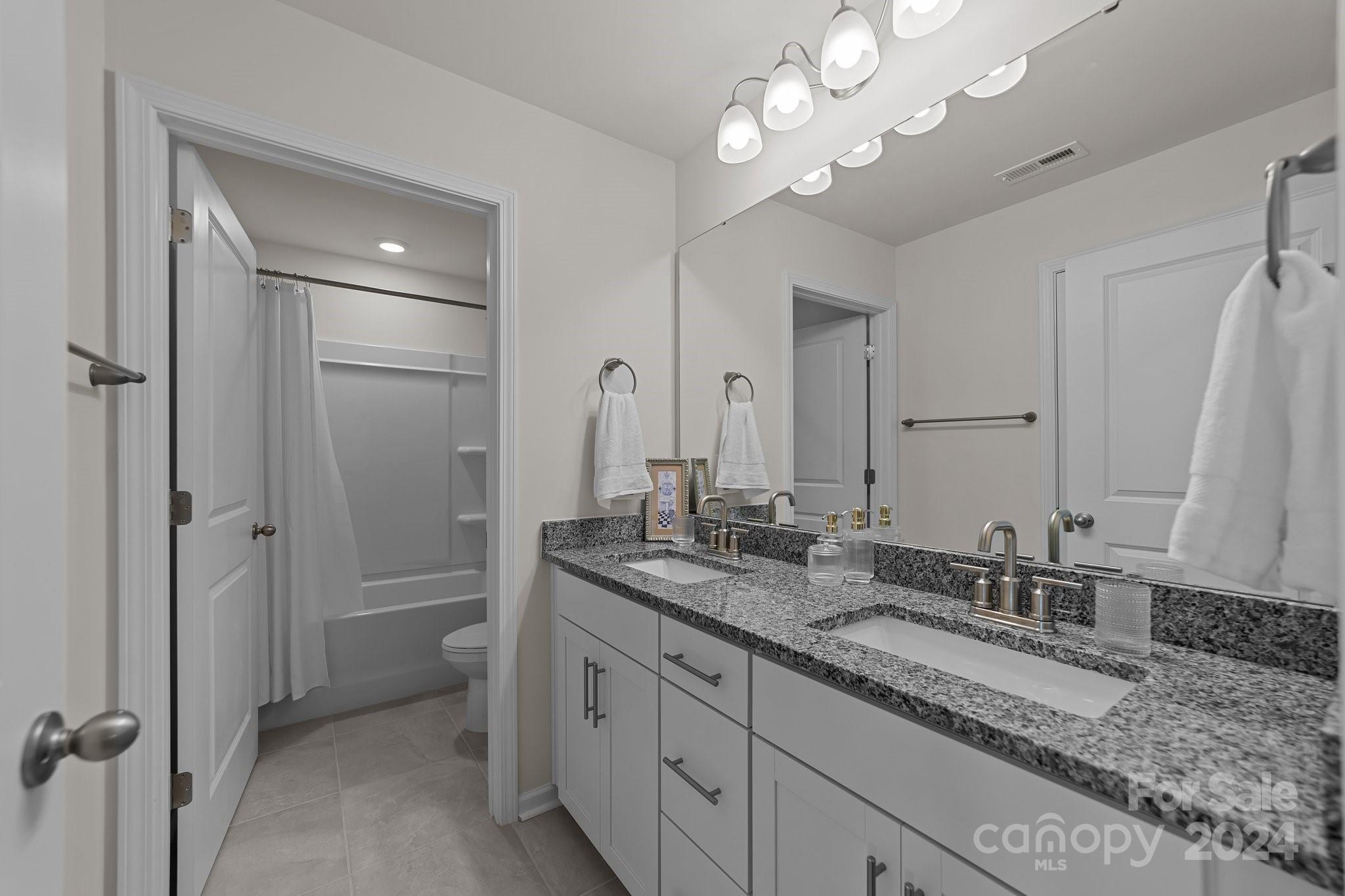 6037 Treehouse Drive Charlotte, NC 28214 - Photo 30 of 48 a bathroom with a granite countertop double vanity sink a mirror and a shower