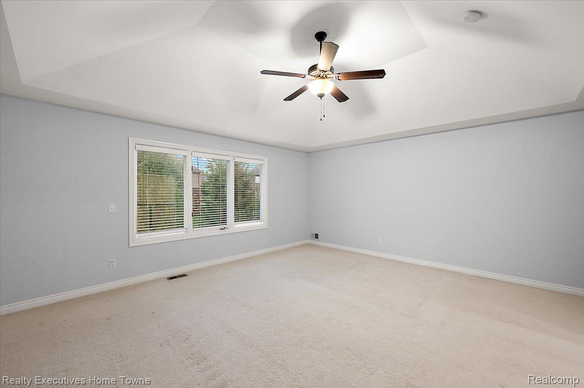 2919 North Addison Circle Rochester, MI 48306 - Photo 38 of 69 Tray ceiling, ceiling fan with integrated lighting, triple window unit, light-toned carpeting, and light-colored walls