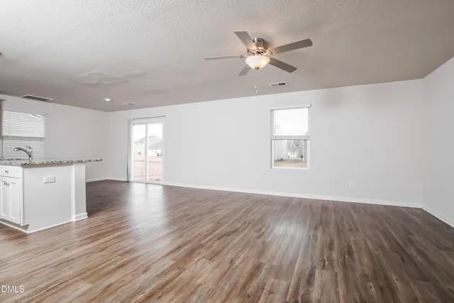 a view of an empty room with a window and wooden floor
