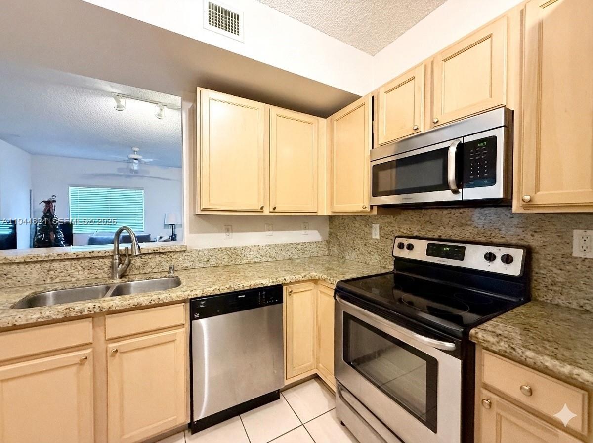 a kitchen with stainless steel appliances granite countertop a stove microwave and sink