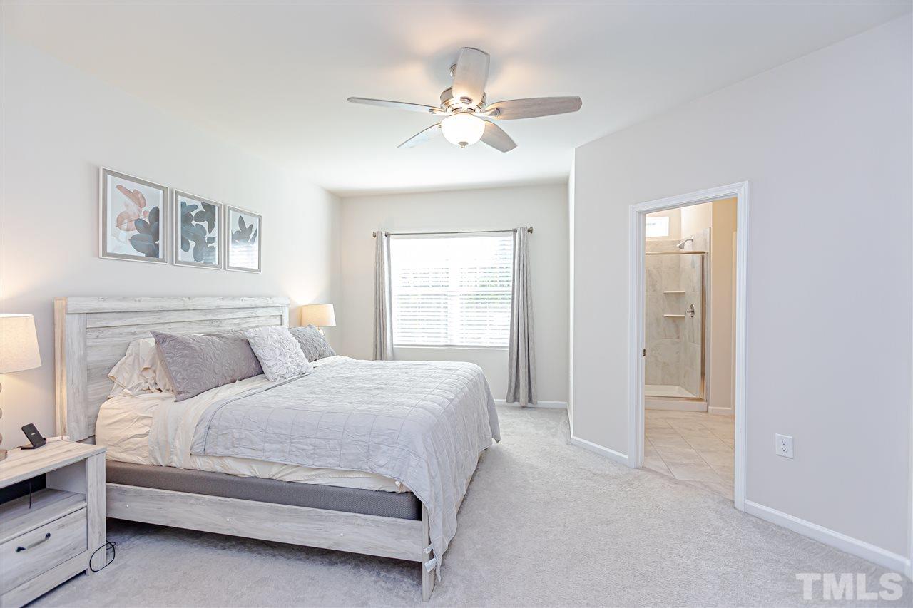 6123 Beale Loop Raleigh, NC 27616 - Photo 17 of 30 a bedroom with a large bed and a chandelier
