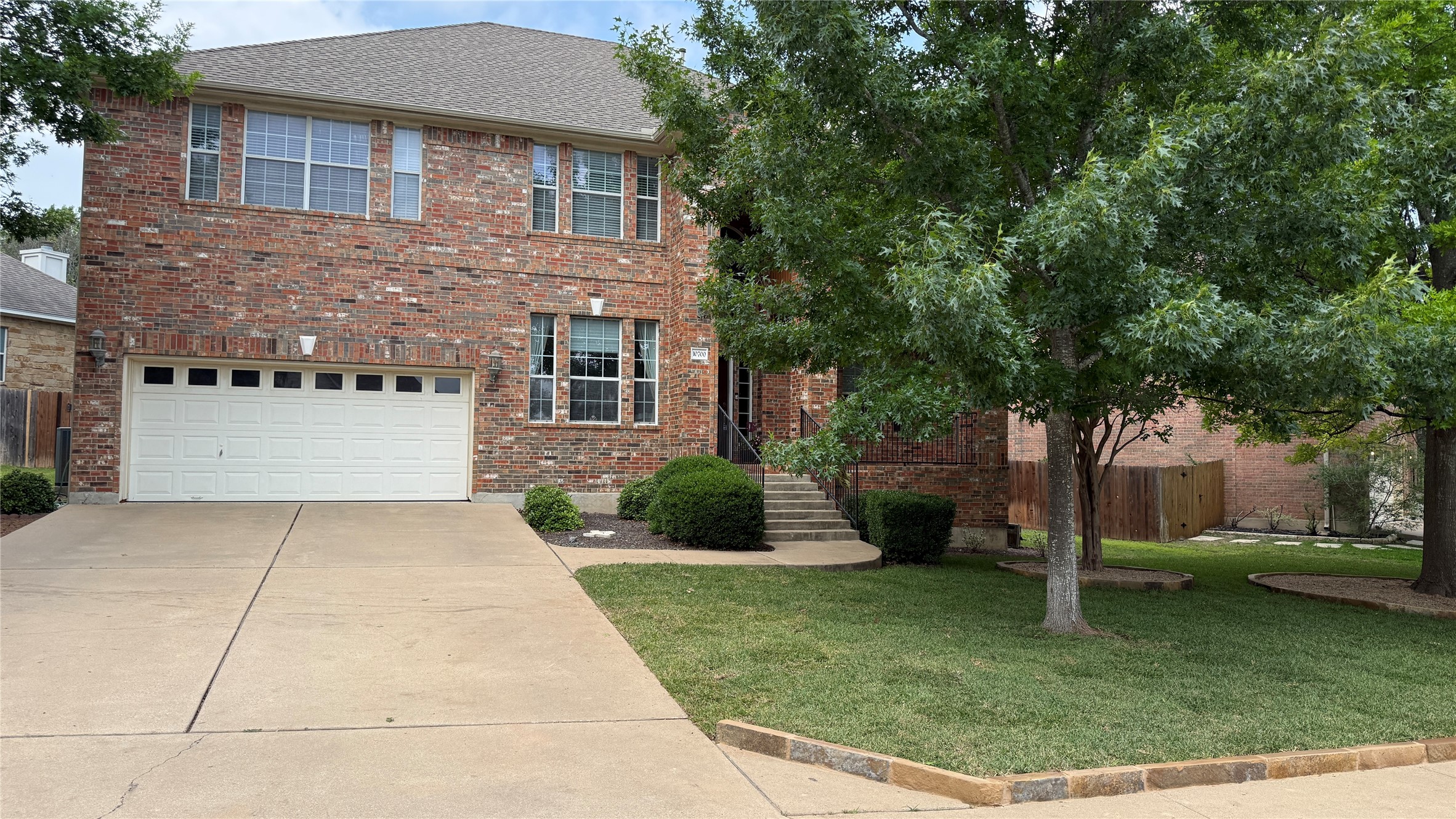 Brick two-story residence featuring a two-car garage, multiple large windows, and a concrete driveway