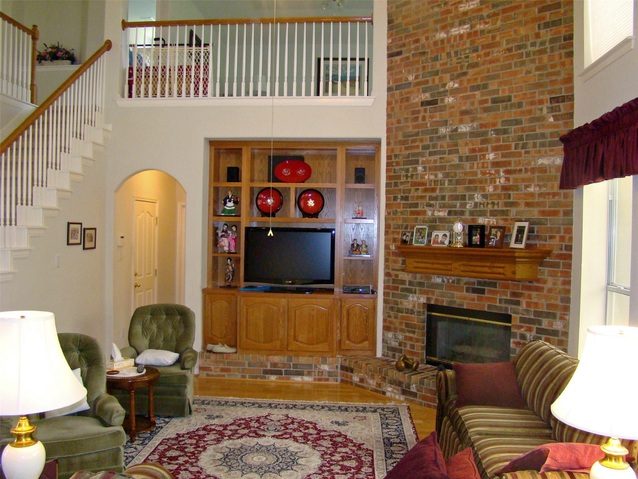 10700 Pointe View Drive Austin, TX 78738 - Photo 12 of 22 Living area with arched walkways, a high ceiling, light wood-type flooring, and a brick fireplace