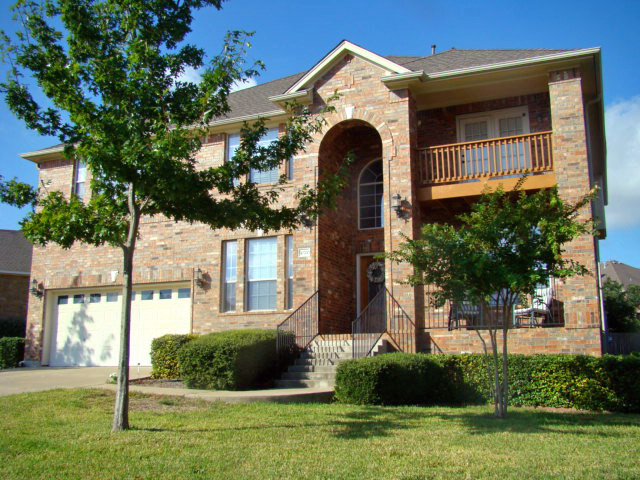 10700 Pointe View Drive Austin, TX 78738 - Photo 4 of 22 View of front facade featuring brick siding, a garage, driveway, and a front yard