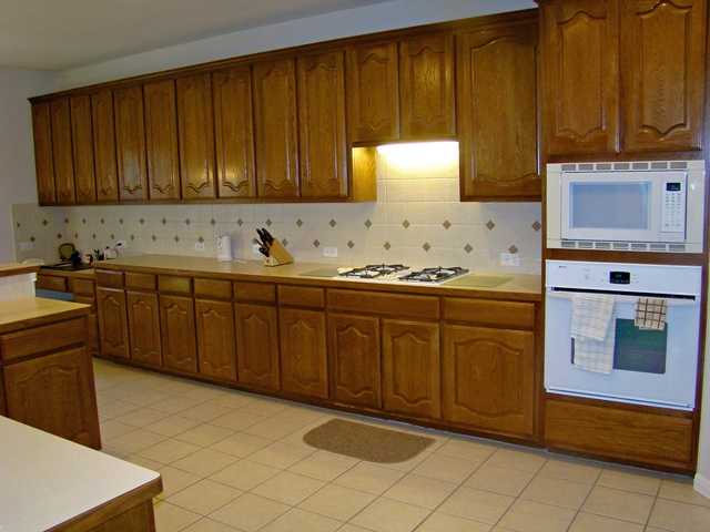 10700 Pointe View Drive Austin, TX 78738 - Photo 6 of 22 Kitchen with wood finish cabinets, white appliances, light countertops, tasteful backsplash, and light tile patterned floors