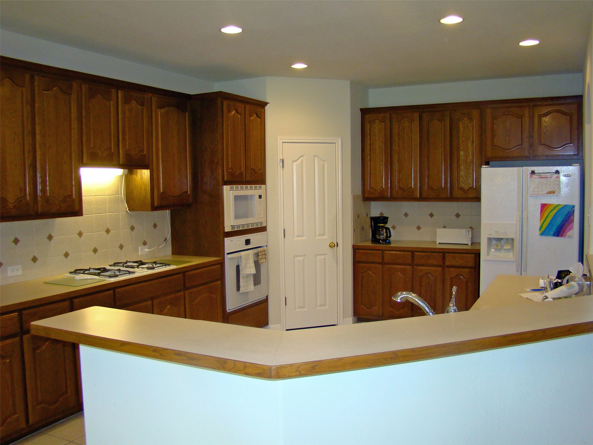 10700 Pointe View Drive Austin, TX 78738 - Photo 7 of 22 Kitchen with white appliances, light countertops, decorative backsplash, recessed lighting, and a kitchen island with sink
