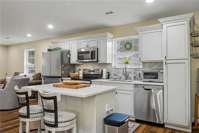 a kitchen with a refrigerator a stove and a sink with wooden floor
