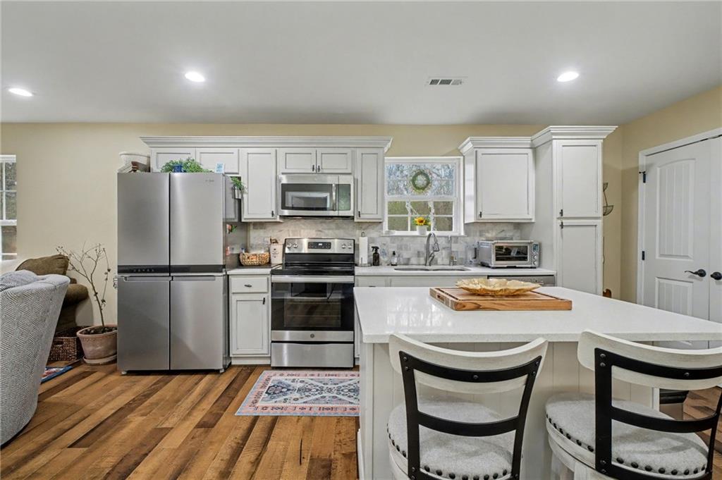 4843 Calhoun Road Northeast Rome, GA 30161 - Photo 18 of 56 a kitchen with a refrigerator a stove and a sink with wooden floor