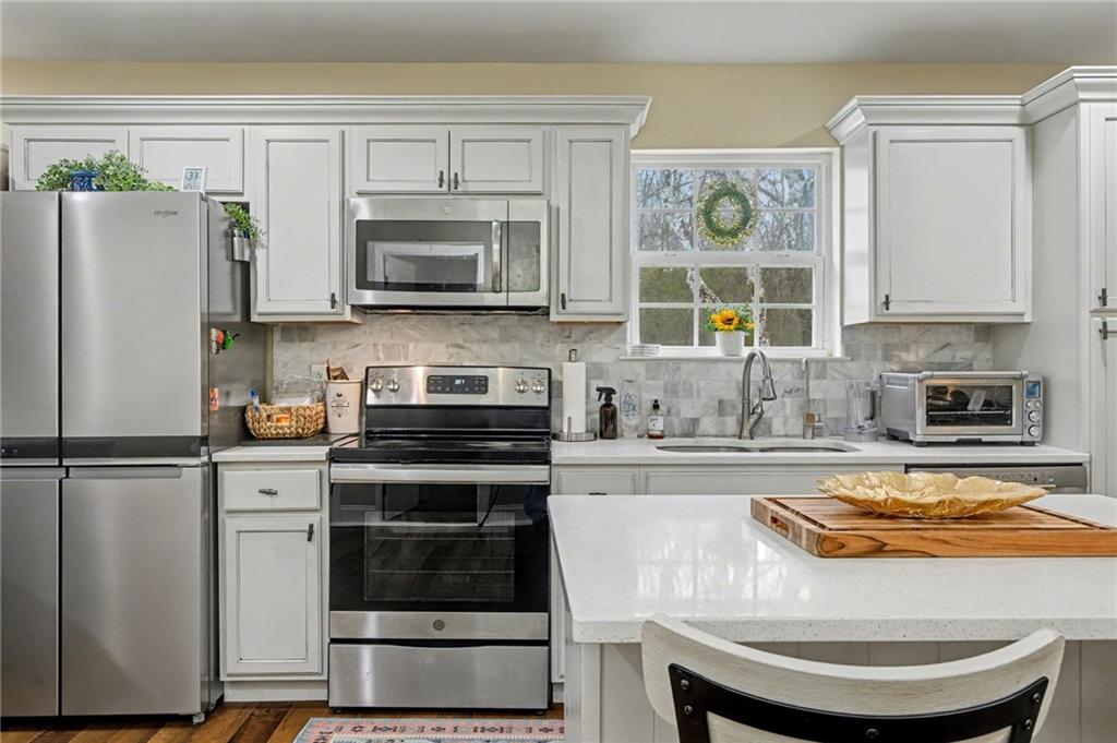 4843 Calhoun Road Northeast Rome, GA 30161 - Photo 19 of 56 a kitchen with stainless steel appliances a stove a refrigerator a sink and white cabinets
