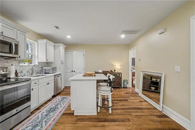 a kitchen with stainless steel appliances granite countertop a stove top oven a sink dishwasher and a refrigerator with wooden floor