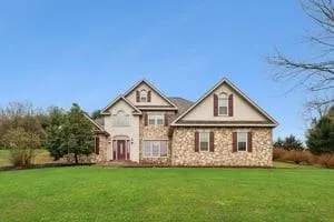 a view of a house with a big yard and large trees