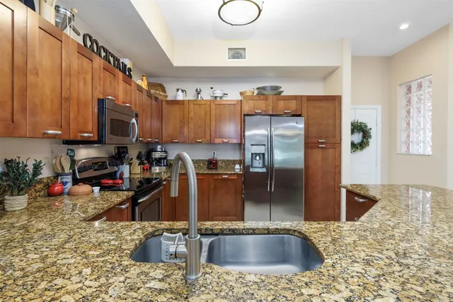 a kitchen with stainless steel appliances granite countertop a refrigerator a stove and a sink with wooden floor