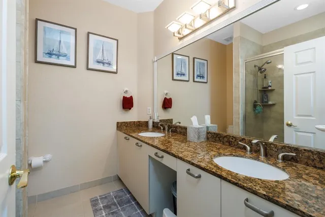 a bathroom with a granite countertop double vanity and a mirror