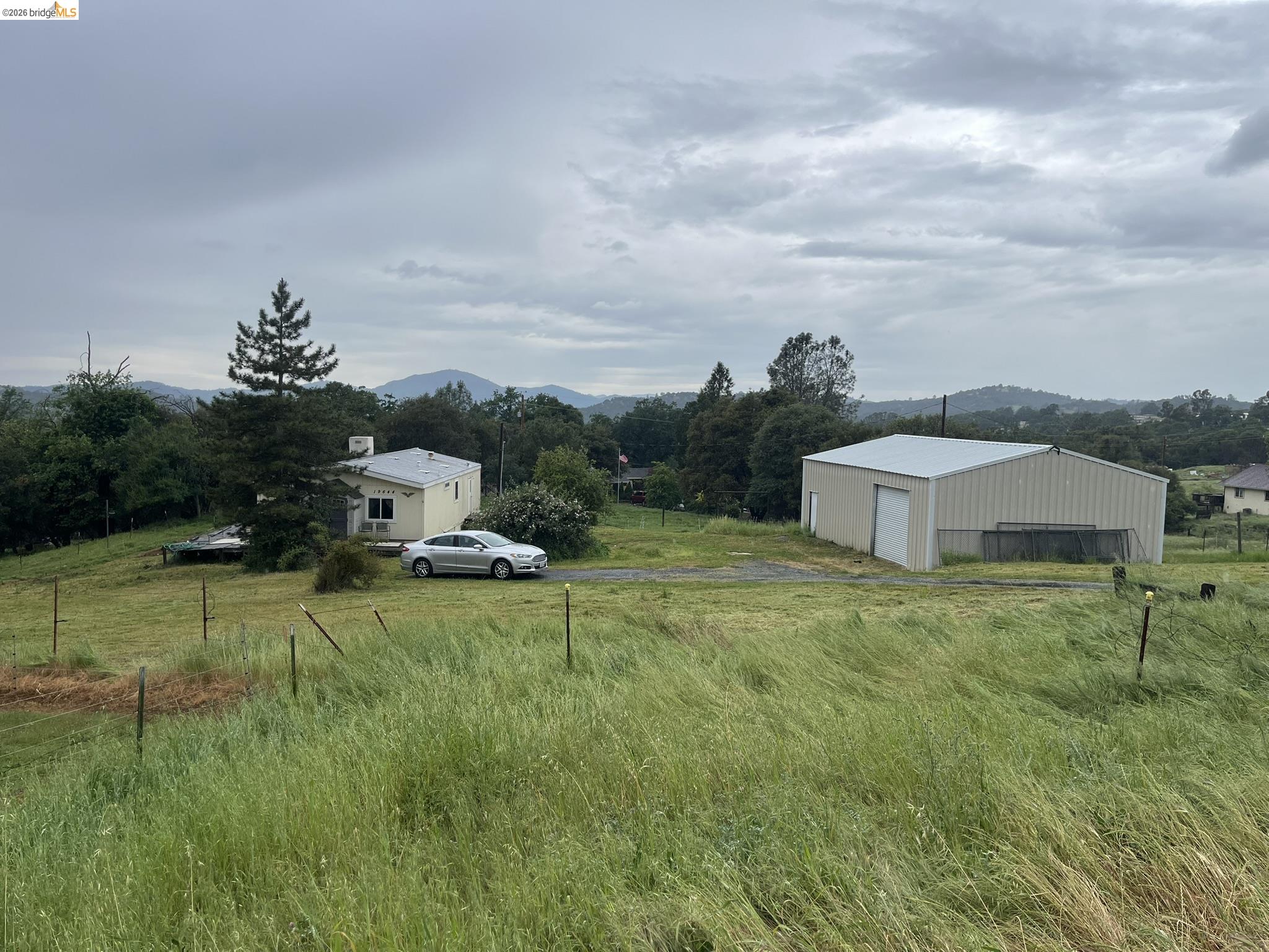 19644 Rawhide Road Sonora, CA 95370 - Photo 2 of 45 View of yard featuring a rural view, an outdoor structure, a pole building, a detached garage, and a mountain view